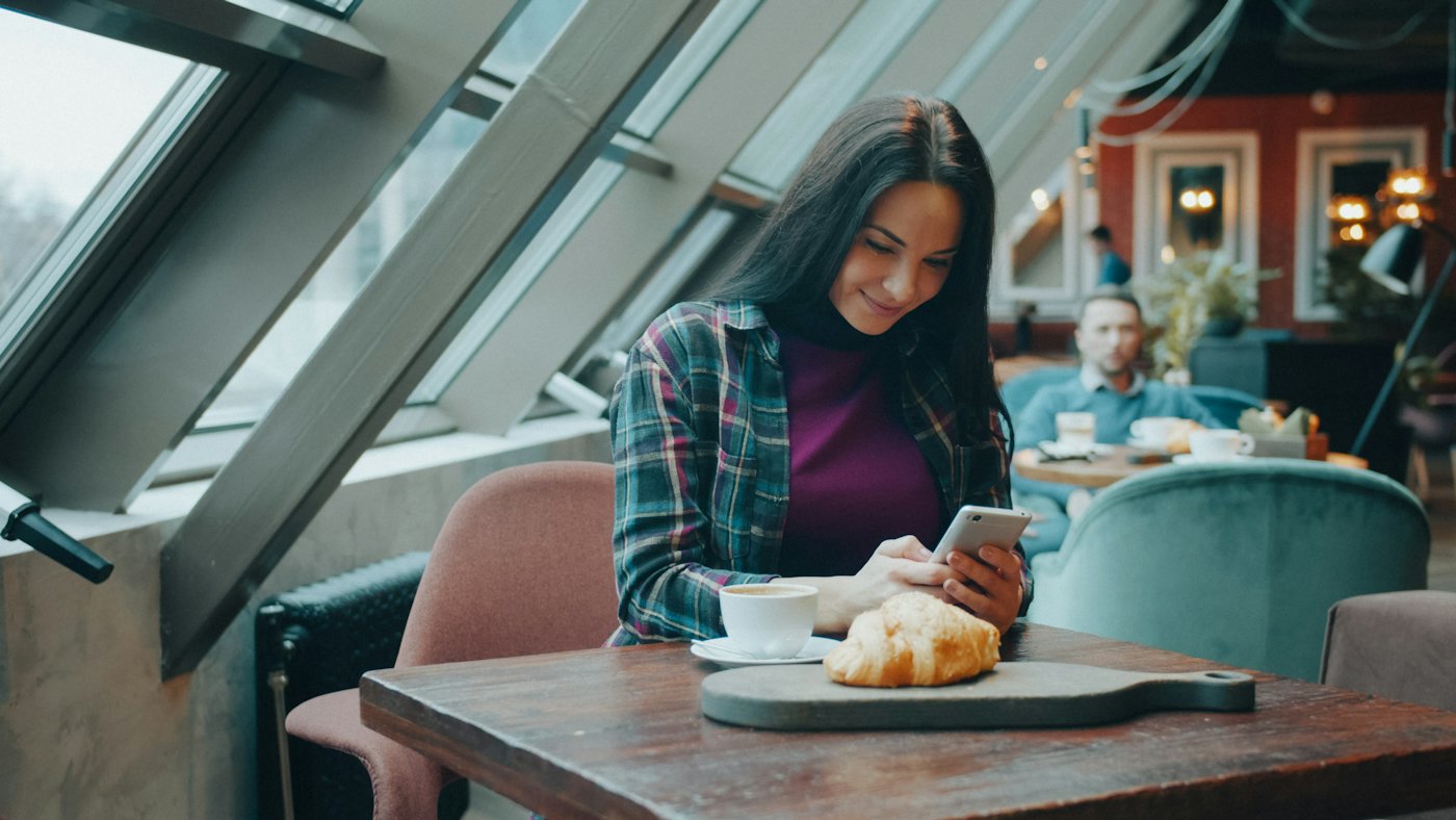 Kundin sucht im Café auf dem Smartphone